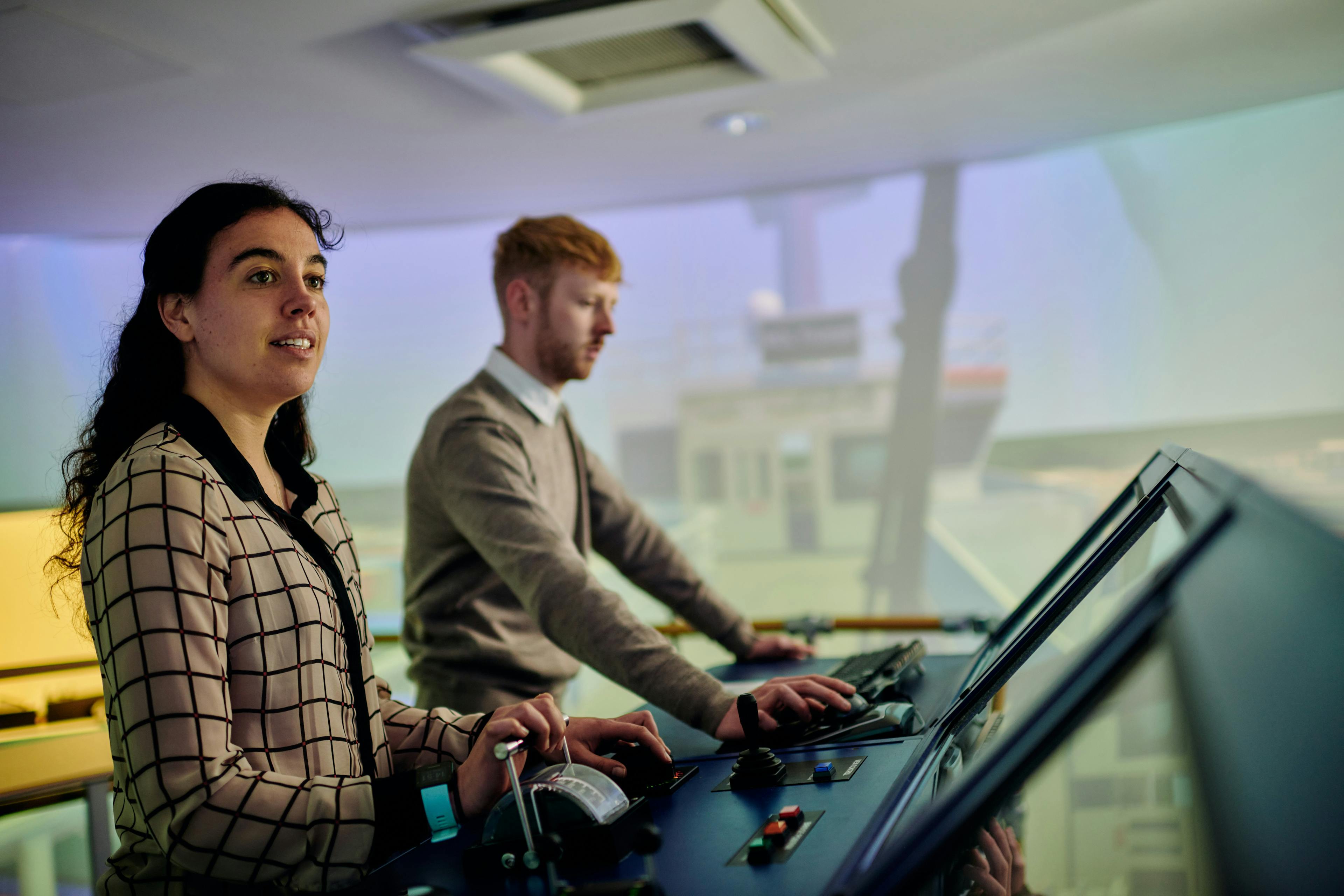 Two people participating in vessel pilot training on the simulator bridge.