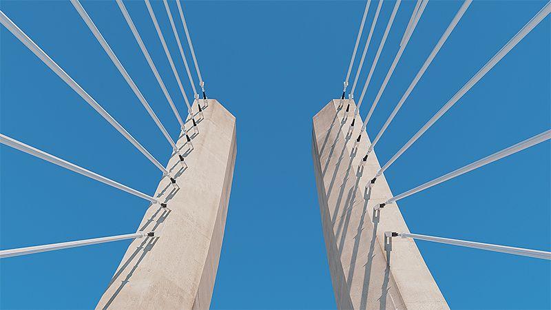 Câbles sur un pont vus du dessous avec un ciel bleu clair en toile de fond