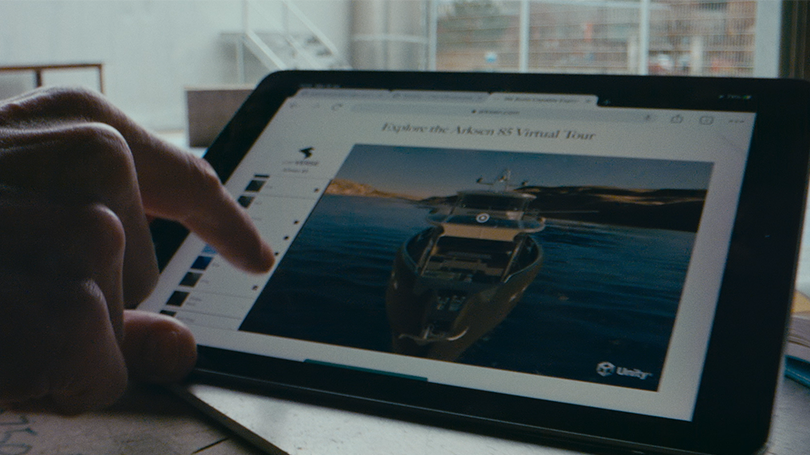 Die Hand zeigt auf das iPad, auf dem ein Boot visualisiert wird