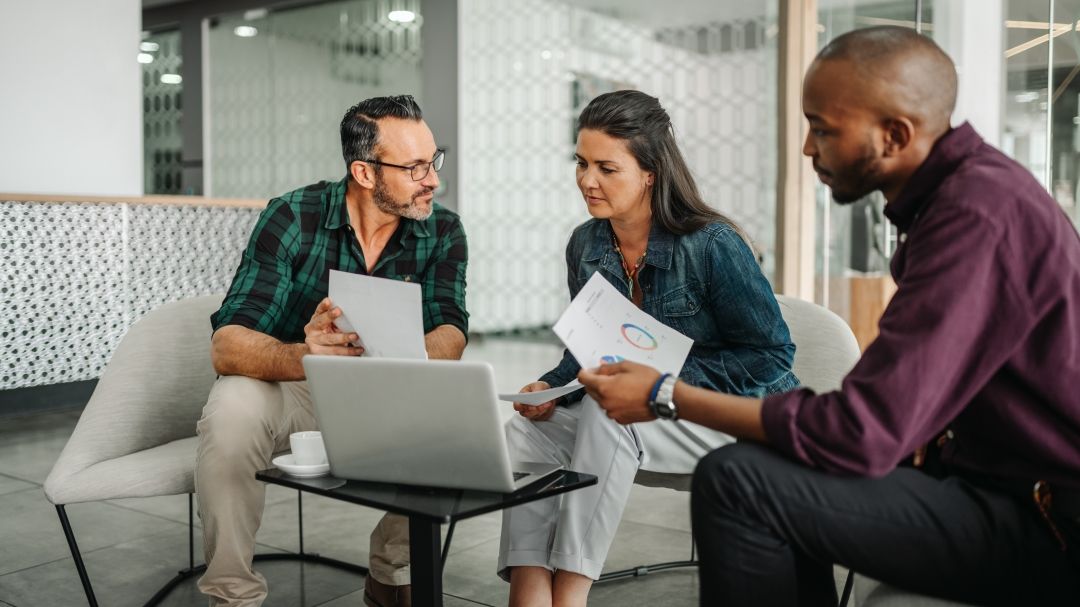 Profesionales de negocios sentados alrededor de una laptop