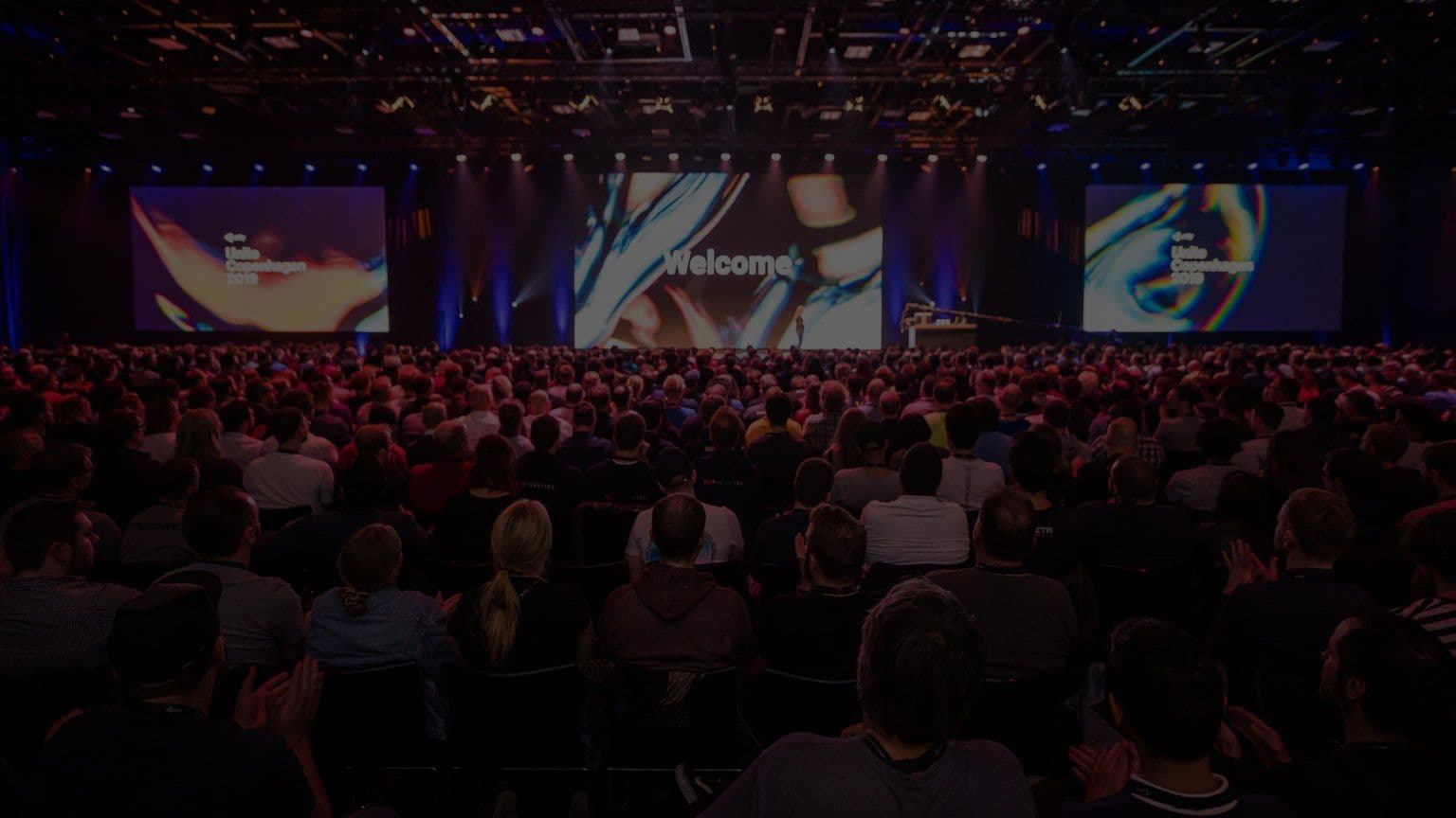 Room full of people in front of stage at a Unite event